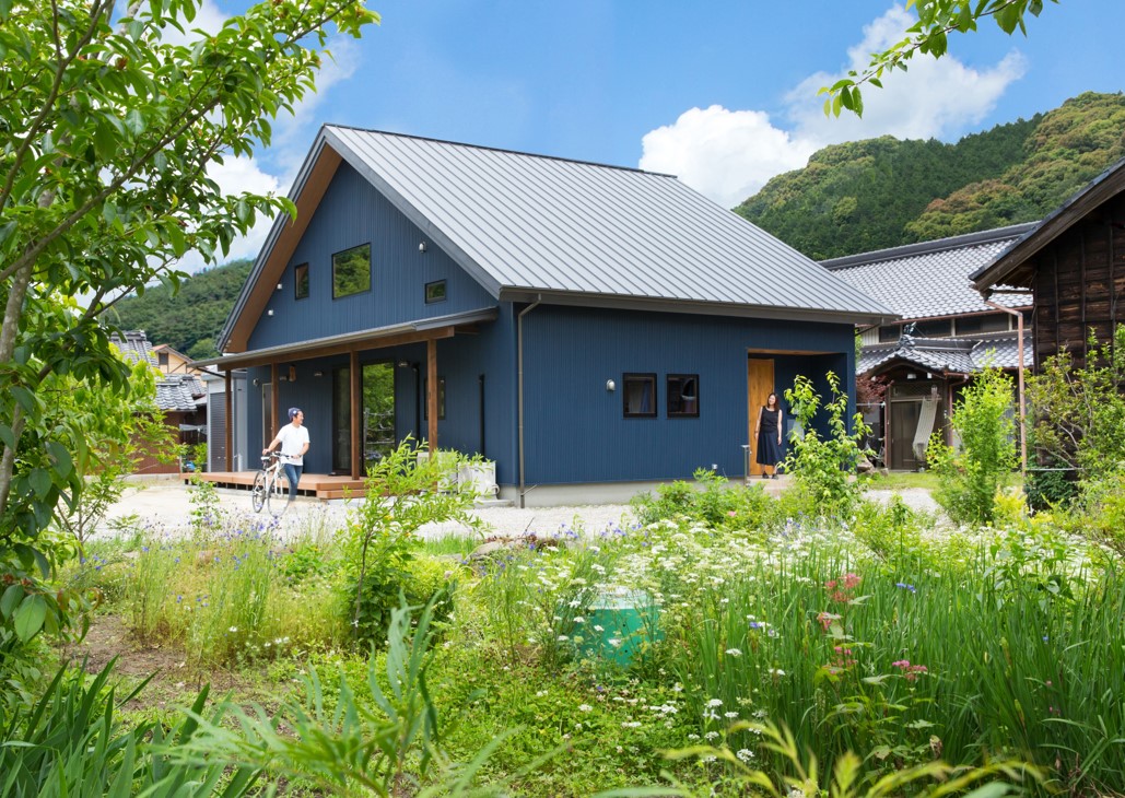 緑の風景になじむネイビーブルーの大屋根の家